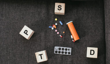 top view of wooden cubes with posttraumatic stress disorder abbreviation signs (PTSD) lying on couch with various pills